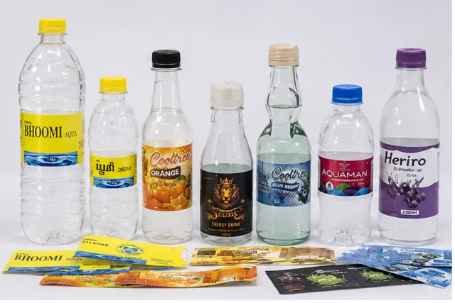 Beverage bottles with different printed labels and loose label samples.